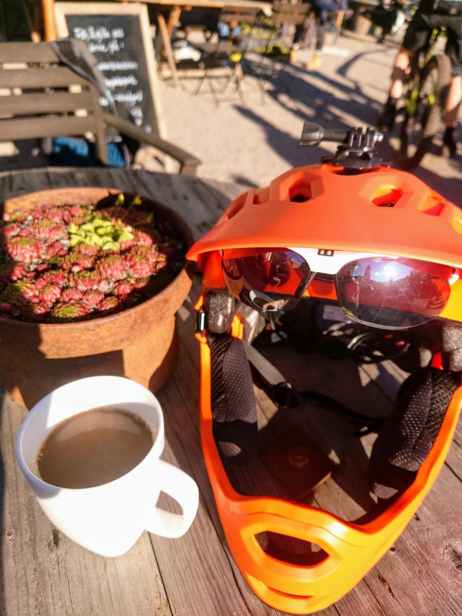 En kaffekopp och en orange hjälm på ett bord i solskenet